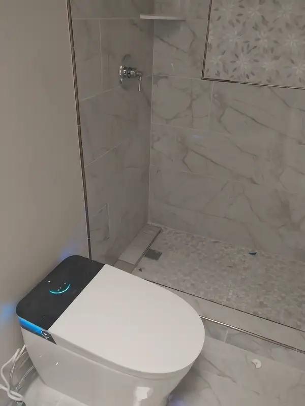 Smart toilet installed next to a tiled walk-in shower