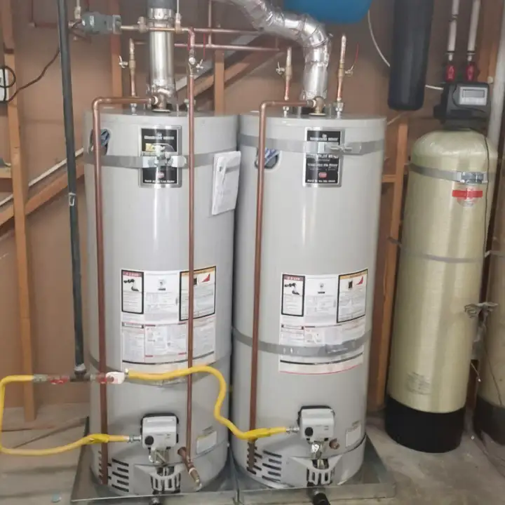 Two gas water heaters installed side by side next to a water softener